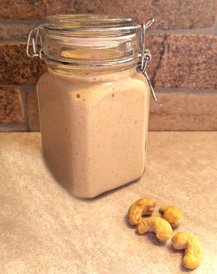 Creamy cashew dressing in a mason jar with cashews.