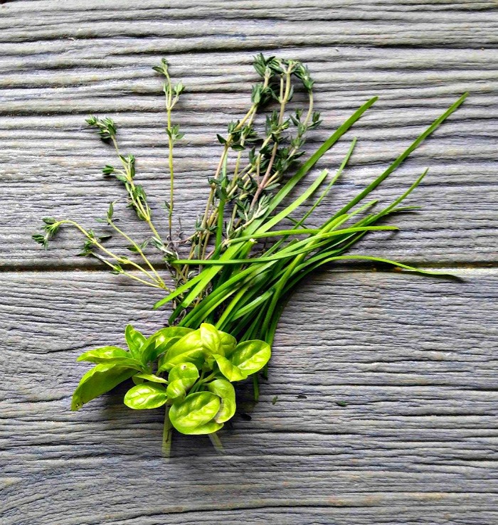 Fresh herbs on a wooden board Fresh thyme, basil and chives