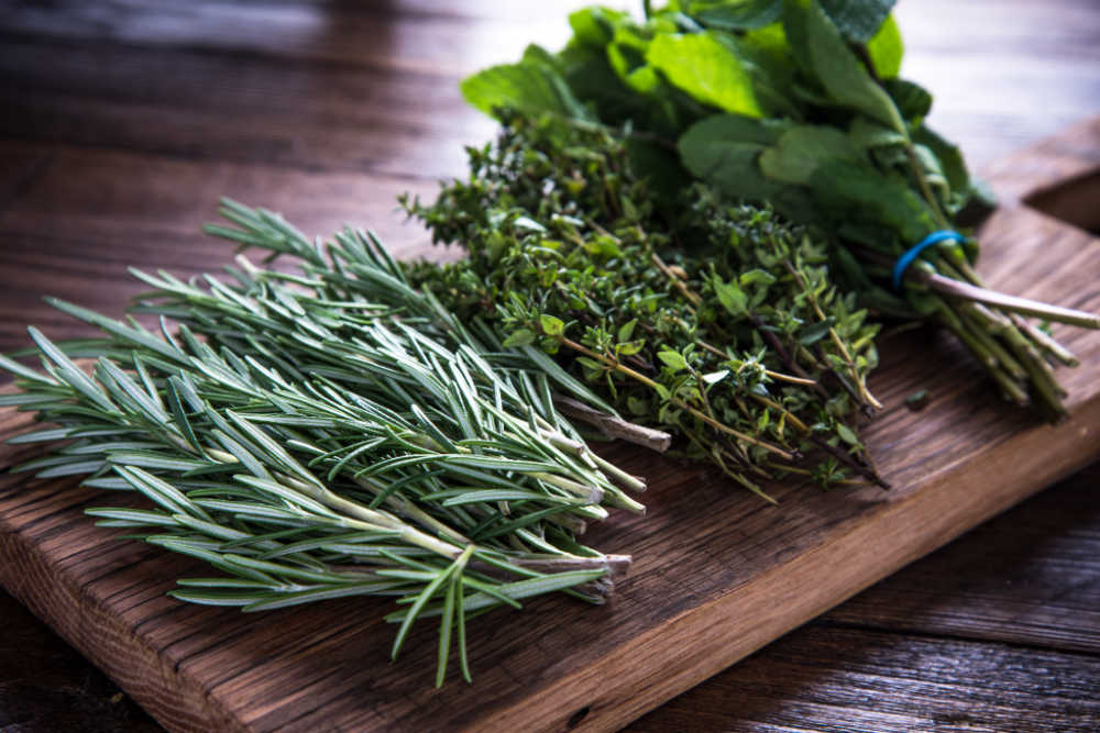 Bunches of fresh herbs on a cutting board.