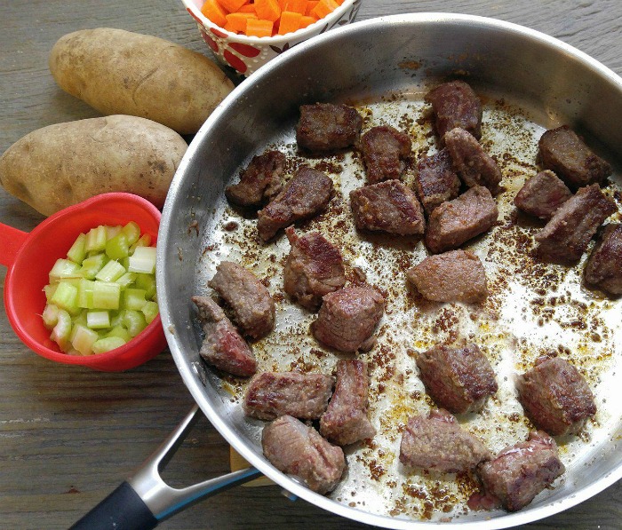 Browned beef in a saute pan and vegetables