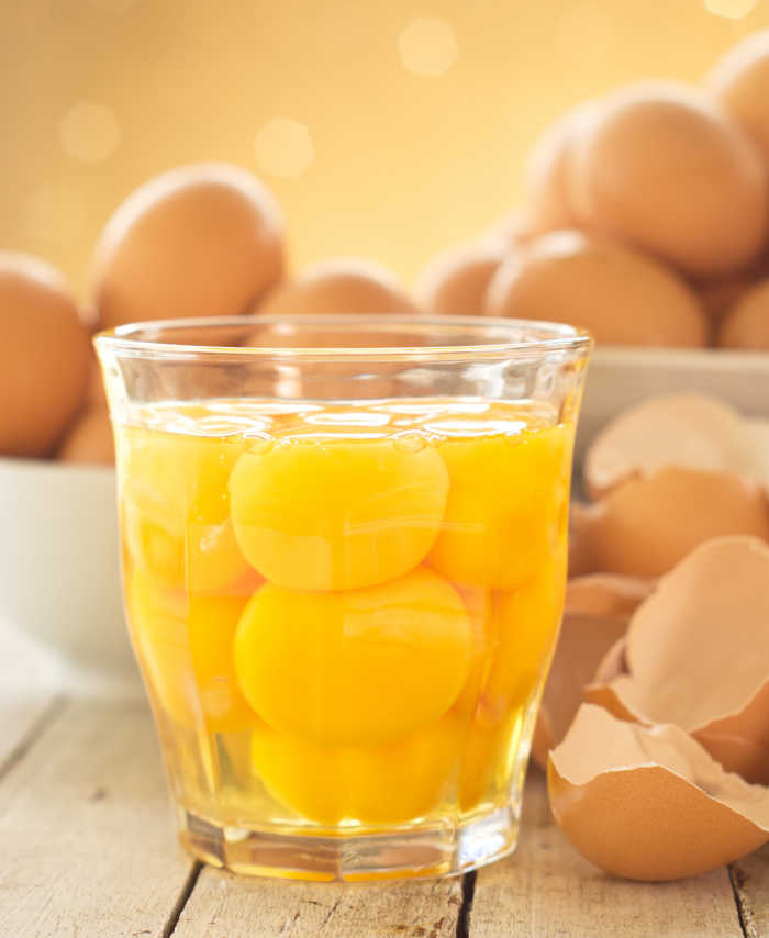 eggs in a clear glass in front of eggs and egg shells.