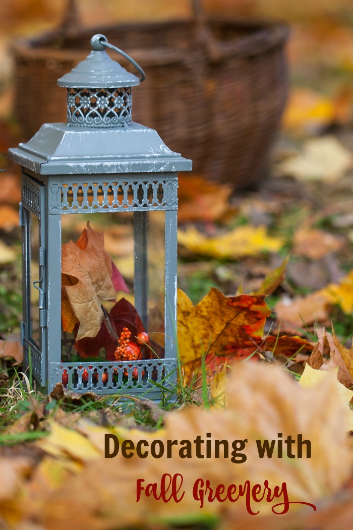 Lantern and leaves with text reading "Decorating with fall greenery."