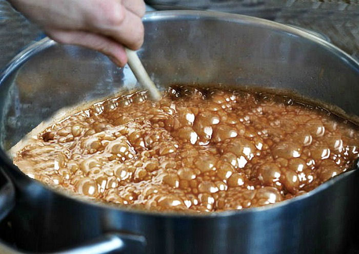 Hand with wooden spoon stirring fudge.