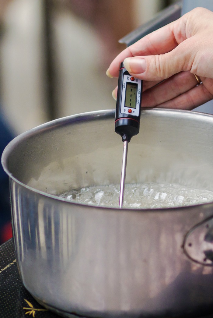 Female hand testing a candy thermometer.