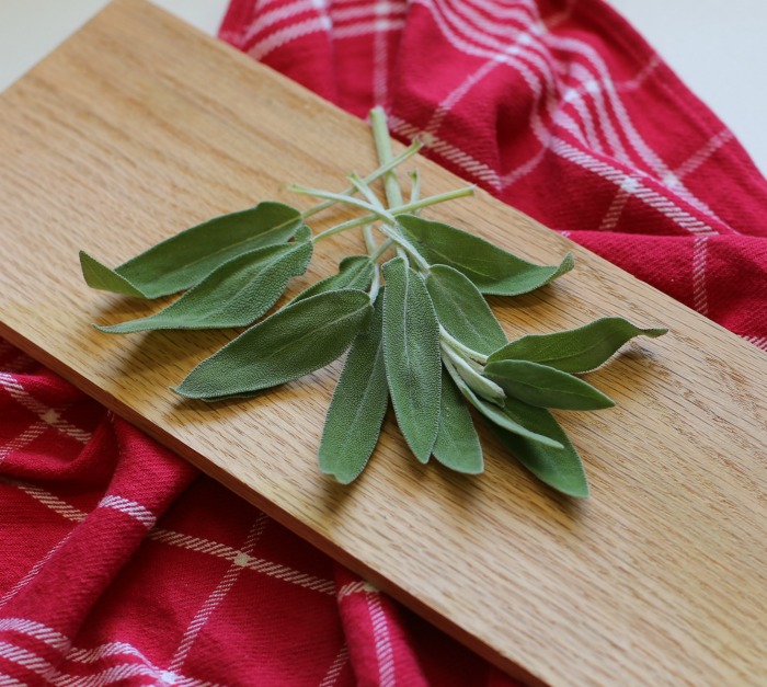 harvested sage plant leaves on a wooden board.