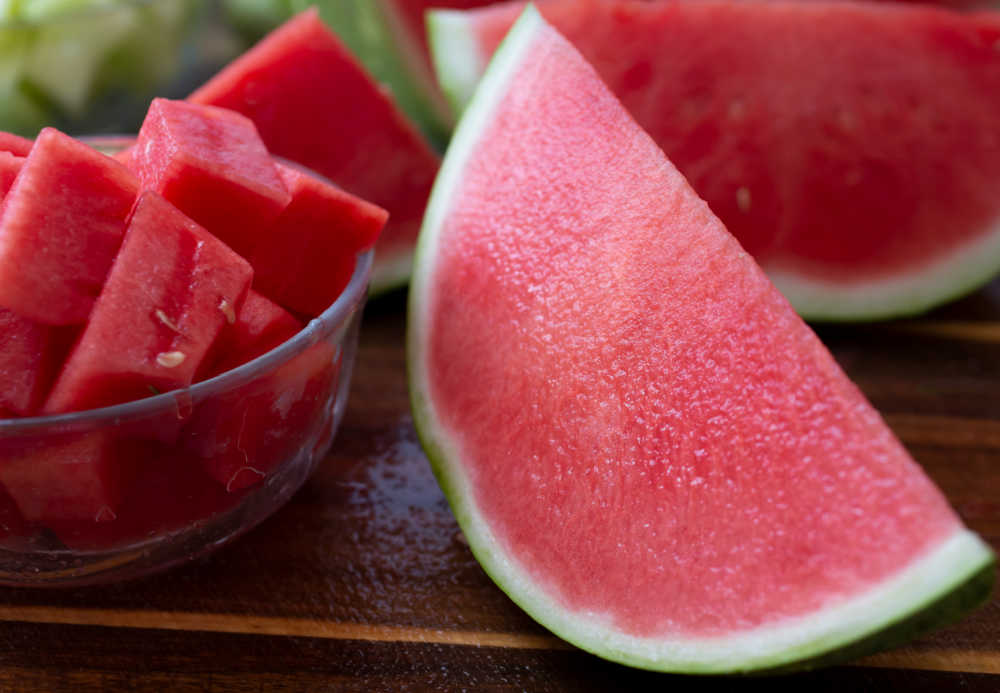 Half a seedless watermelon and bowl of cut slices.