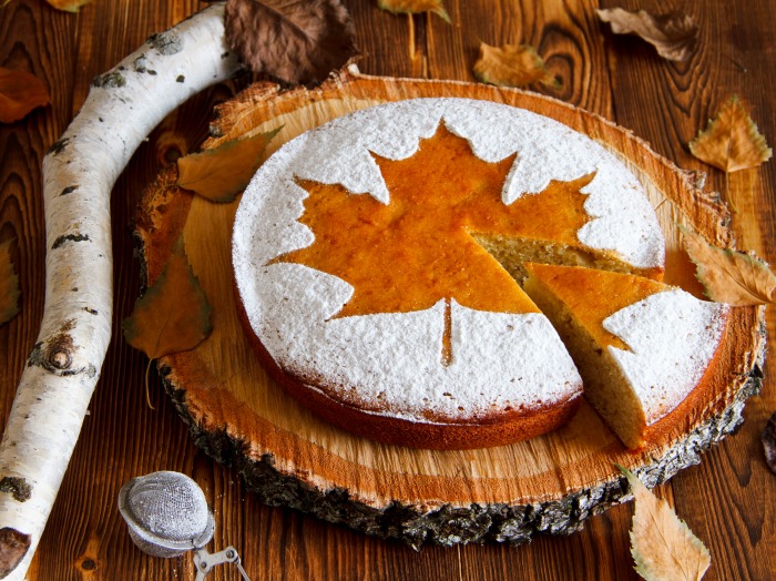 Stunning dessert setting with a maple leaf and powdered sugar Cake with a maple leaf design and powdered sugar round it.