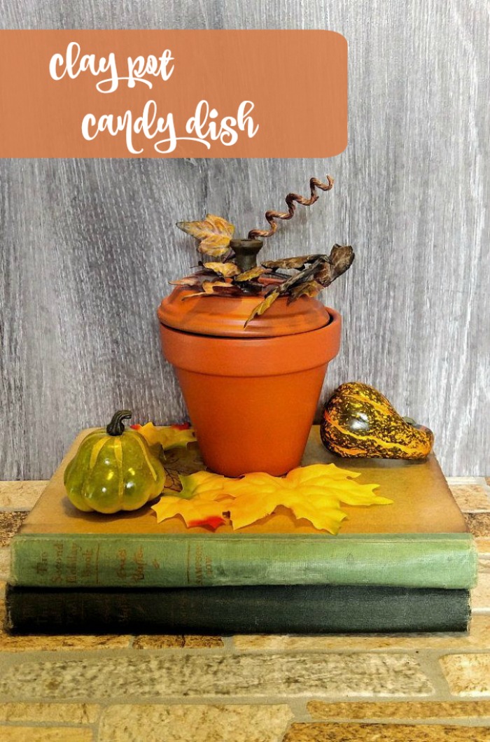 Terra cotta pumpkin Candy dish made of a clay pot on a stack of vintage books