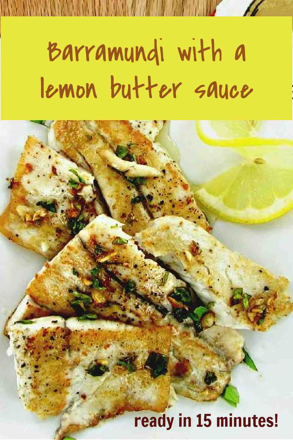Cooked fish on a plate with lemon and words Barrramundi with a lemon butter sauce.