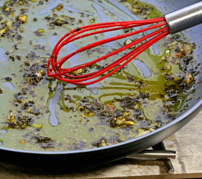 lemon butter sauce for fish in a nonstick skillet with a red whisk.