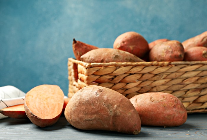 A basket of healthy sweet potatoes and a cut sweet potato.