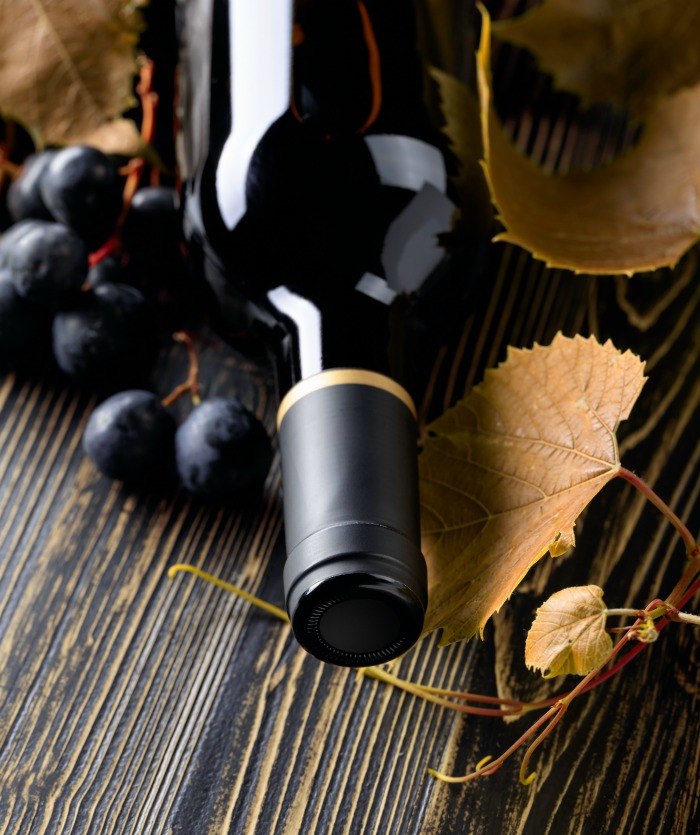Bottle of Merlot wine with grapes and leaves.