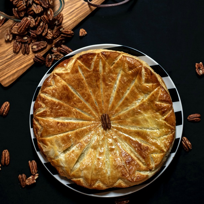 Pithivier pie crust that is made with scored lines in the dough and pecans loosely around it. Pithivier pie crust
