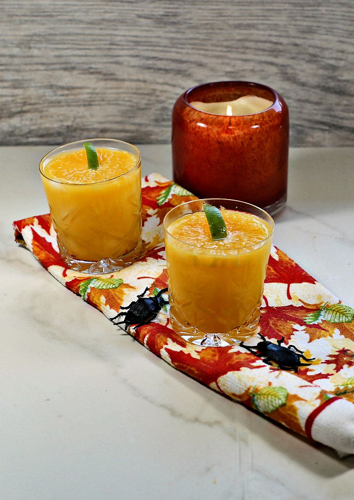 Pumpkin top garnishes made with orange slices ono a fall towel with an orange candle.