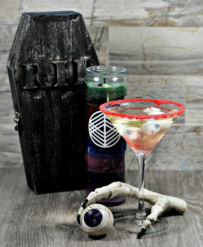 Halloween cocktail with bloody eye gumballs garnish in wine with Halloween props.