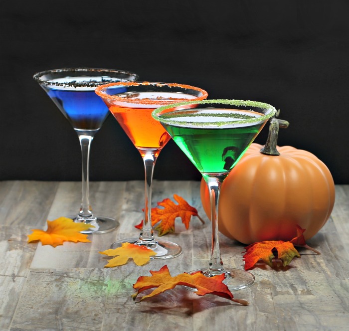 Colored salt on glass rims for Halloween with pumpkin and leaves.