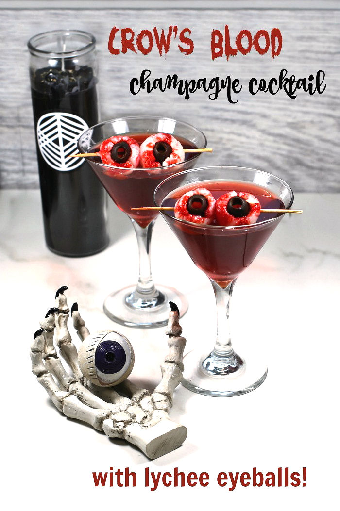 Crow's blood Halloween drink with lychee eyeballs, black candle and skull hand with eye.