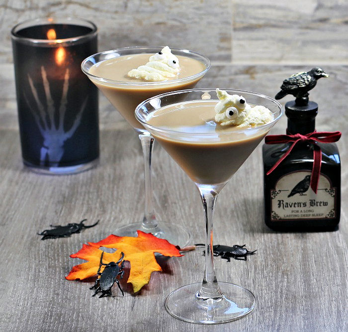 Whipped cream ghosts in a creamy cocktail with candle, bugs and jar.