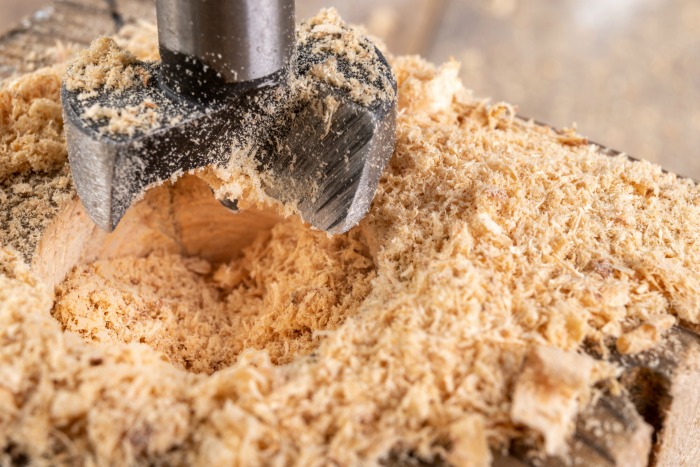 Drilling holes in a log with a Forstner bit.