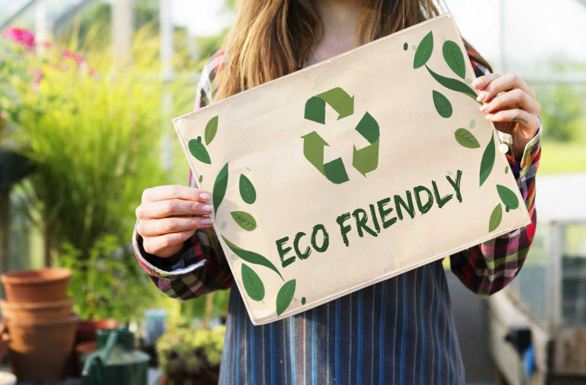 Girl in a garden show holding a sign that says "eco-friendly."