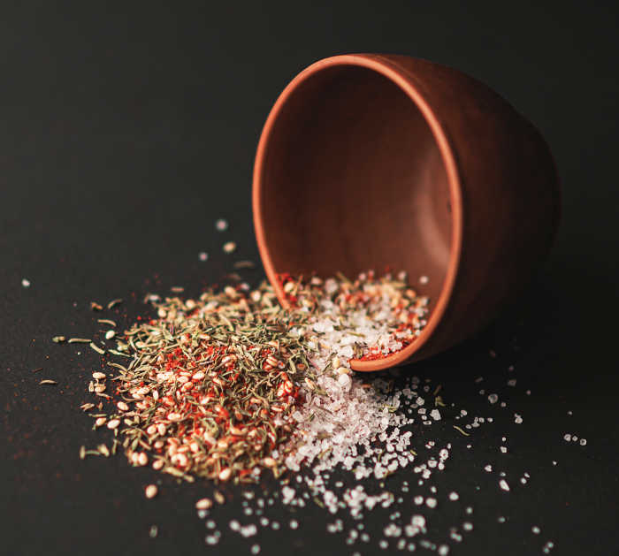 Chicken wing seasoning falling out of a bowl.