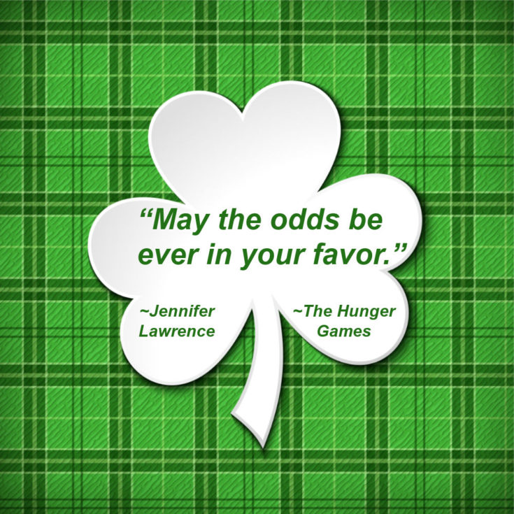 Plaid background with shamrock and words "May the odds be ever in your favor" - Jennifer Lawrence The Hunger Games."