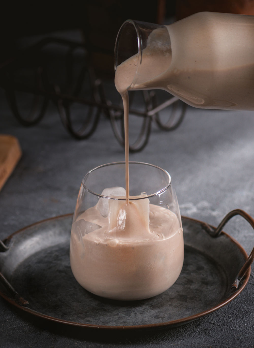 Pouring Baileys Irish cream from a jug into a class with ice.