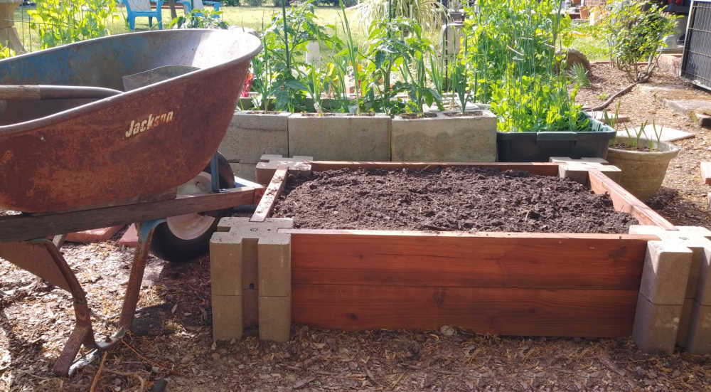 Wheel barrow and shovel with soil for a raised garden bed.