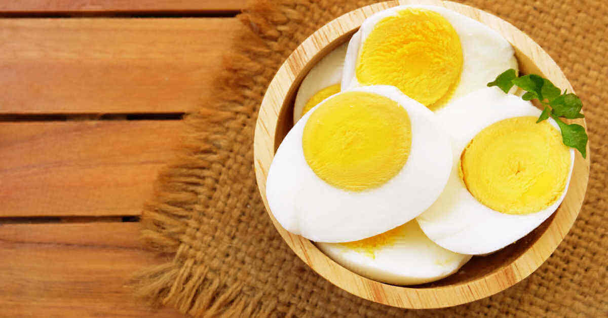 Sliced hard boiled eggs in a bowl with herbs.