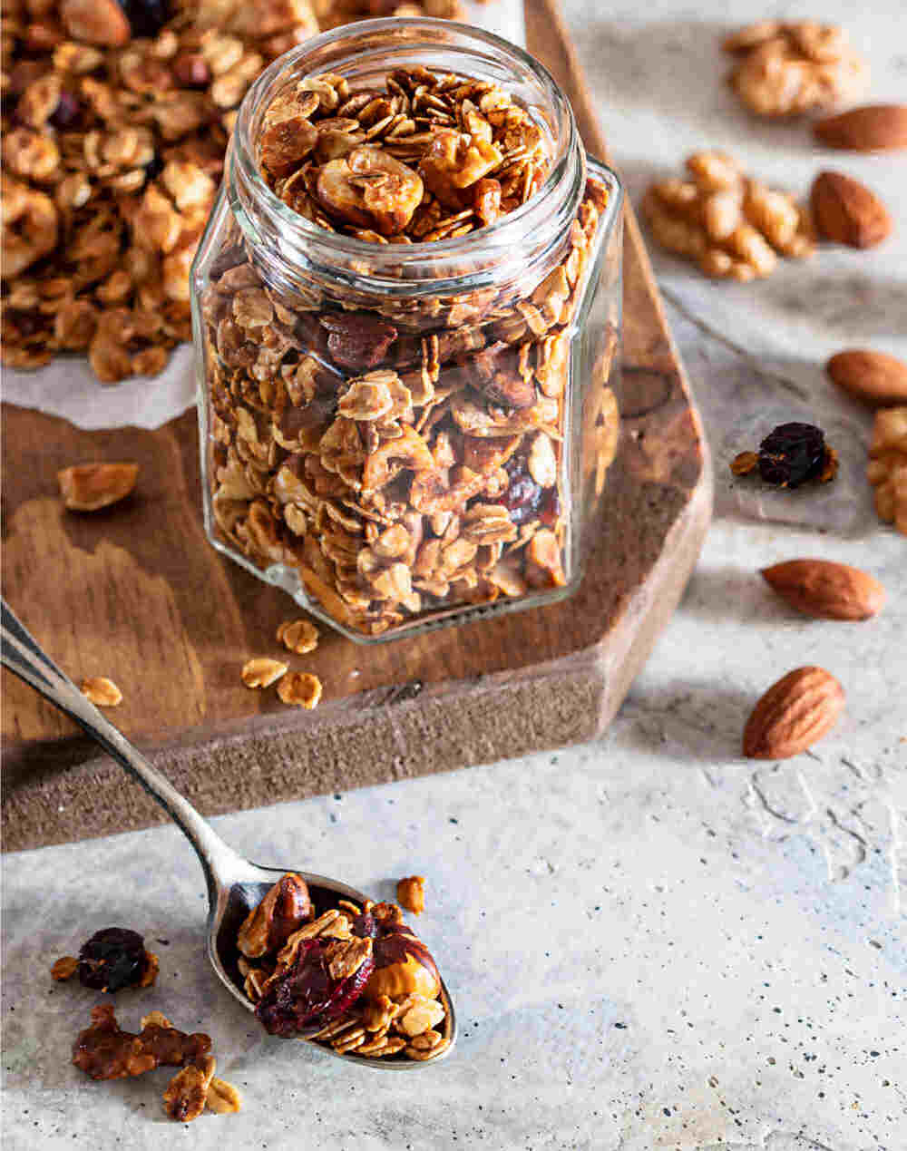 Homemade granola in a jar with spoon, nuts and dried fruit.