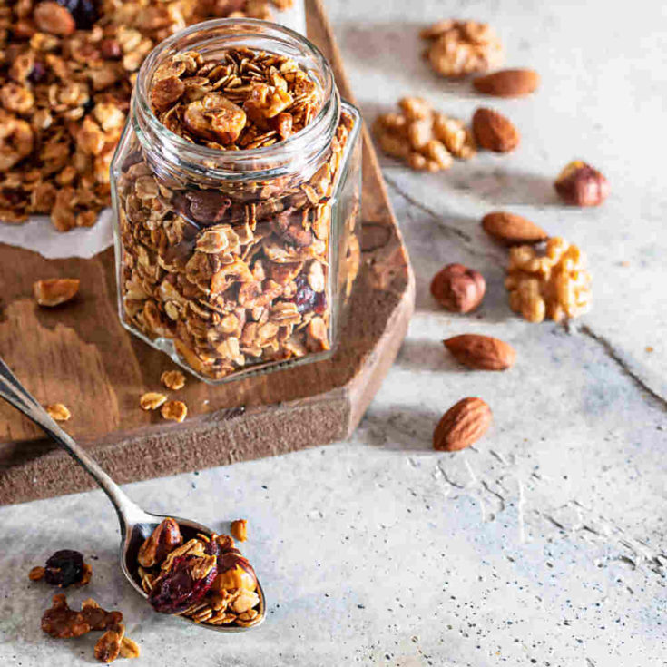 Healthy granola in ajar with a spoon and nuts.