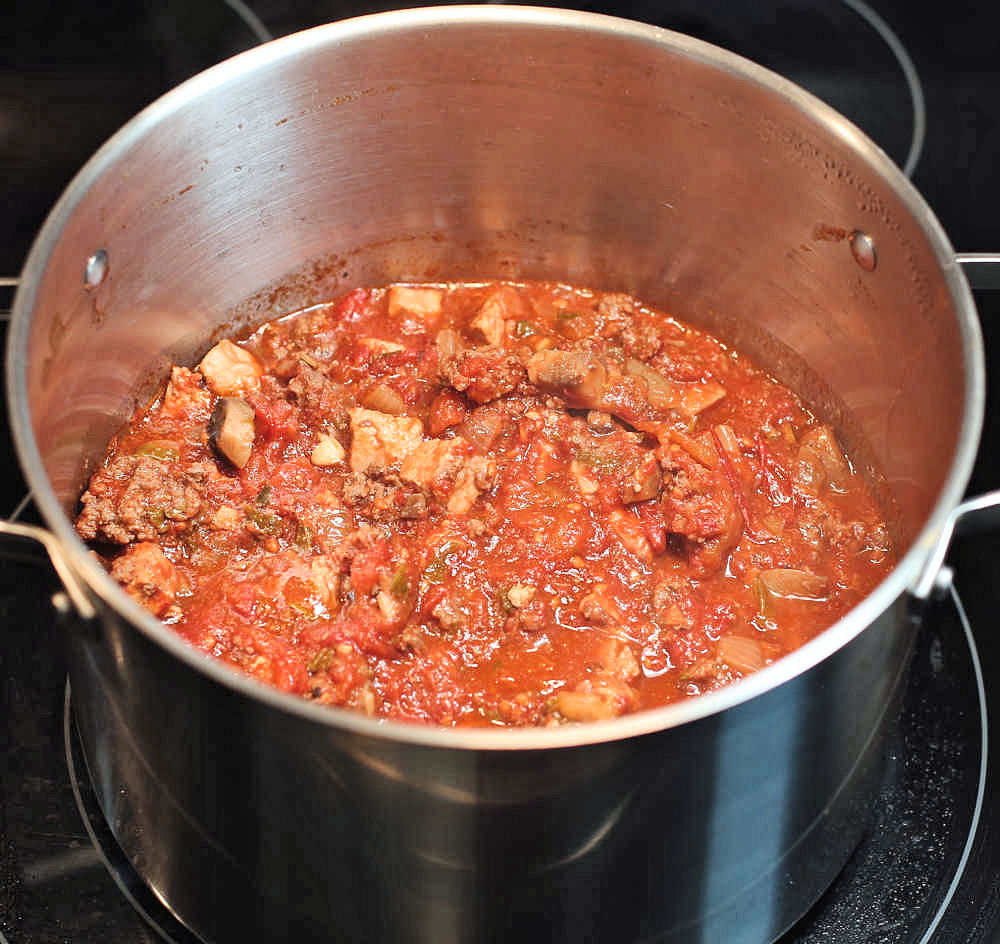 Thick spaghetti sauce with pork and beef, onions and mushrooms in a bit pot.