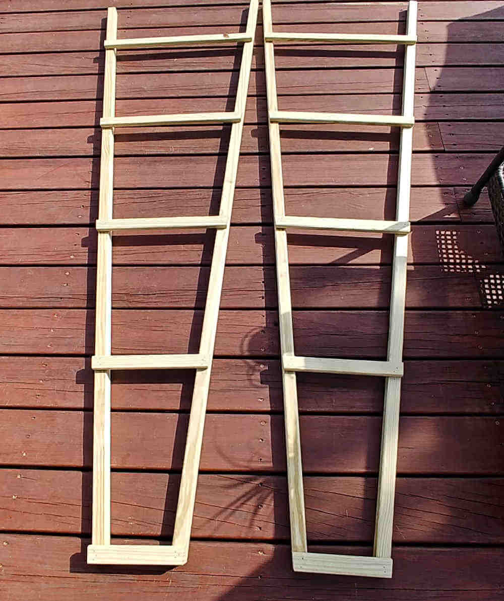 Ladder supports for an obelisk on a wooden deck.