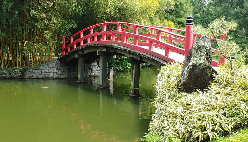 Red curved bridge over a pond