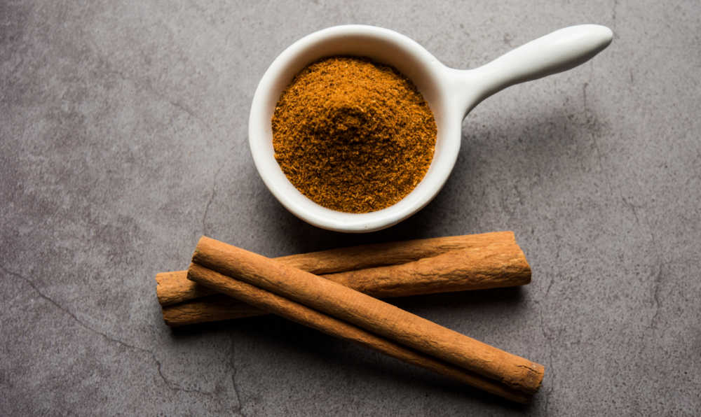 ground cinnamon and cinnamon sticks. Ground cinnamon next to cinnamon sticks.