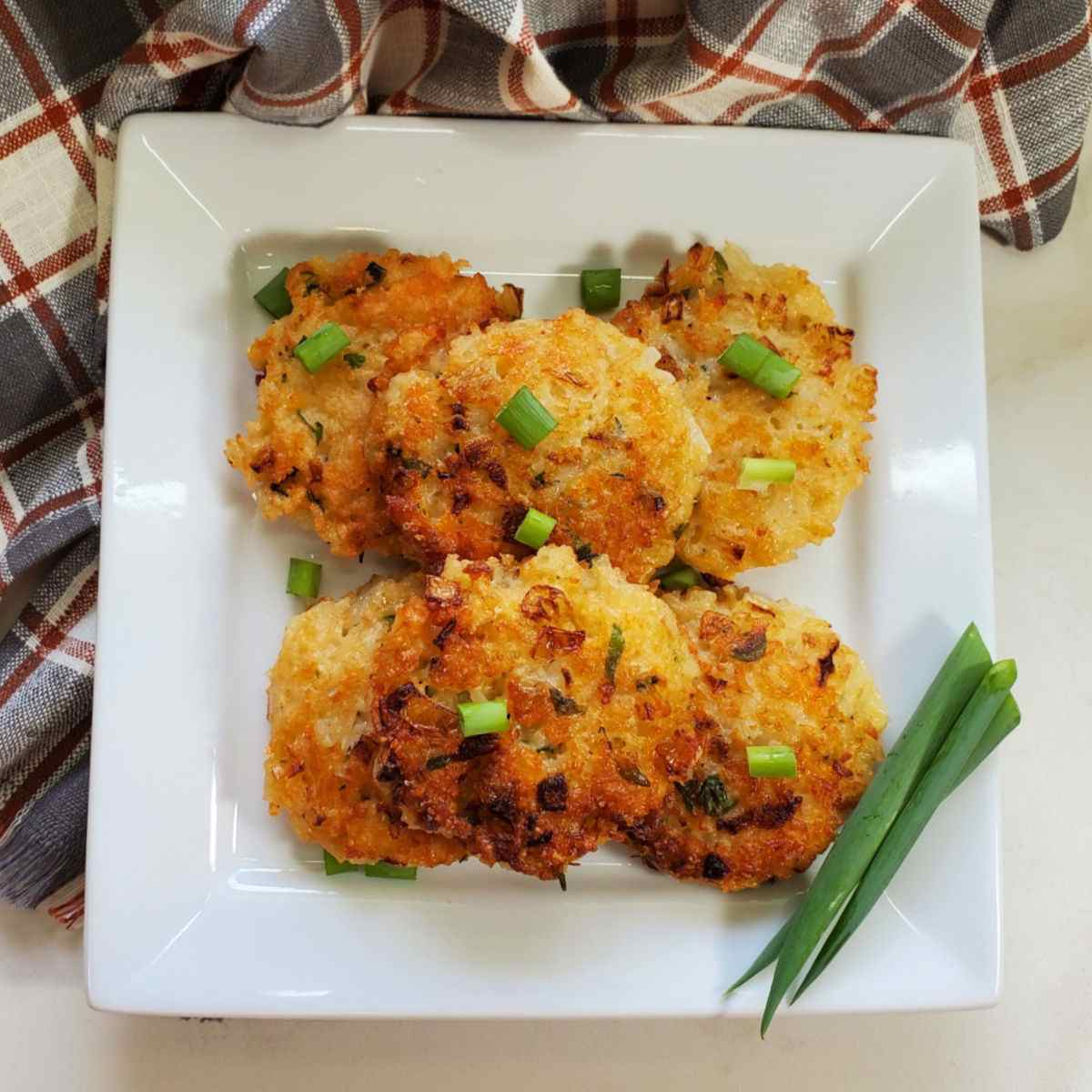 Fried rice patties on a plate with spring onions.